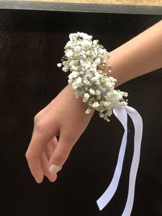 a person's hand holding a bouquet of white flowers on top of a black box