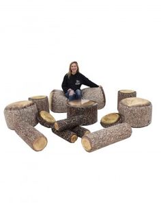 a woman sitting on top of a tree stump chair next to several pieces of wood