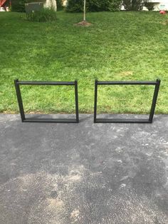 two black metal frames sitting on top of a cement floor in front of a grass covered yard