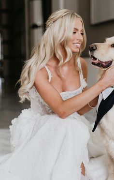 a woman in a wedding dress sitting next to a white dog wearing a tuxedo