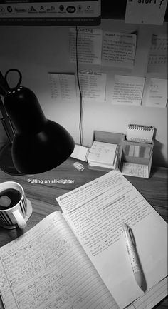 an office desk with coffee, notebooks and pen on it in black and white