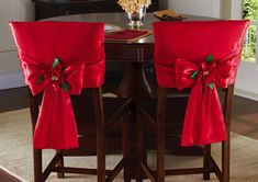 two red chairs with bows on them sitting in front of a table and chair cover