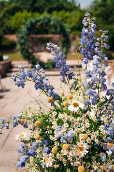 a vase filled with lots of blue and white flowers next to a wooden table outside