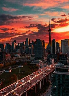 the sun is setting over a city with tall buildings and cars driving on the road