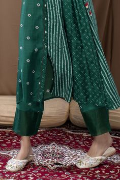 Deep green tunic with bandhani prints, side gathers and tie-up. Paired with bandhani pant.
Component: 2
Pattern: Printed
Type Of Work: Bandhani
Neckline: Collar
Sleeve Type: Three Quarter
Fabric: Cotton Silk
Color: Green
Other Details: 
Front button down tunic
Embroidered sleeves cuffs
Side tassel tie-up
Occasion: Puja - Aza Fashions Festive Bandhani Print Palazzo Set In Mulmul, Traditional Bandhani Print Palazzo Set For Designer Wear, Festive Bandhani Print Mulmul Palazzo Set, Designer Bandhani Print Palazzo Set For Navratri, Traditional Bandhani Print Palazzo Set For Navratri, Green Bandhani Print Traditional Wear For Transitional Season, Traditional Bandhani Print Palazzo Set For Festive Occasions, Festive Traditional Palazzo Set With Bandhani Print, Green Traditional Wear With Bandhani Print For Festive