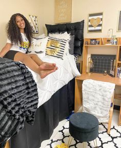 a woman sitting on top of a bed next to a black and white rug in a bedroom