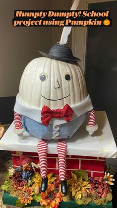 a decorative pumpkin sitting on top of a pile of books with a hat and bow tie