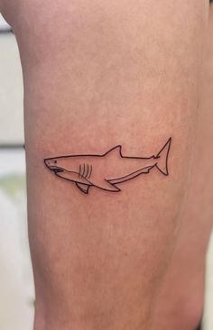 a small shark tattoo on the thigh