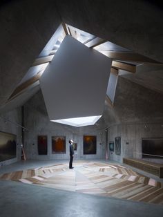 a person standing in an empty room with paintings on the walls and ceiling lights above them