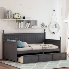 a day bed with drawers underneath it in a room that has white walls and wooden floors