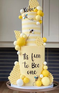 a three tiered cake decorated with honeycombs and bees on the side, says it's fun to bee one