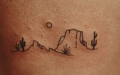 a small tattoo on the side of a woman's stomach with mountains in the background