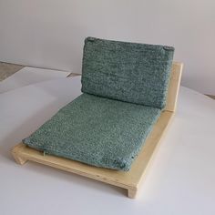 a chair that is sitting on top of a wooden frame with a green seat cushion