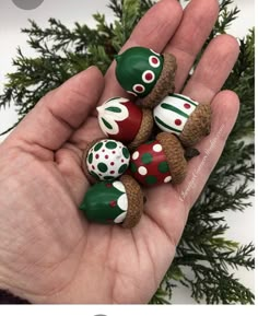 a hand is holding five small chocolates in it's palm, with green and red designs on them