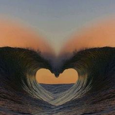 a heart shaped wave in the ocean at sunset