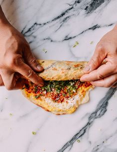 two hands reaching for a piece of food on a marble surface