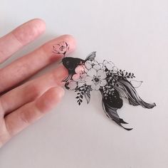 a person's hand holding a sticker with flowers and a fish on it