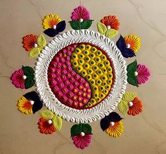 an intricately decorated plate with colorful flowers on the floor in front of a marble wall