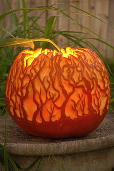 an orange carved pumpkin sitting on top of a cement slab with fire coming out of it