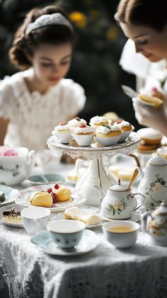 two women sitting at a table with tea and pastries