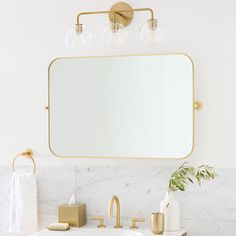 a bathroom with marble countertops and gold fixtures, including a large mirror above the sink