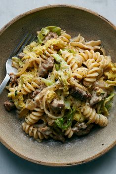 a bowl filled with pasta, meat and broccoli on top of a table