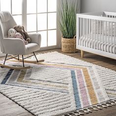 a baby's room with a rocking chair, crib and rugs on the floor