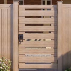 a large wooden gate is shown in front of a house with flowers and bushes around it