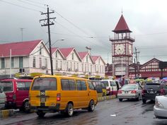 many cars are parked on the side of the road in front of buildings and a clock tower