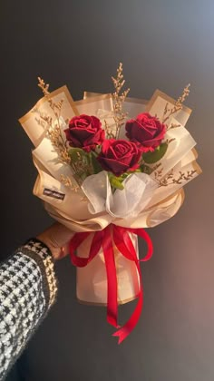 a person holding a bouquet of roses in their hand with the ribbon tied around it