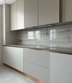 a kitchen with white cabinets and marble counter tops