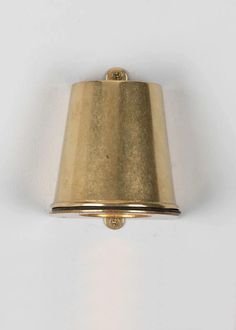 a wall light with a gold shade on it's side and a white background