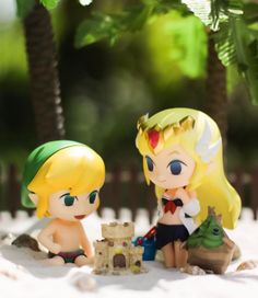 two figurines sitting next to each other in the sand