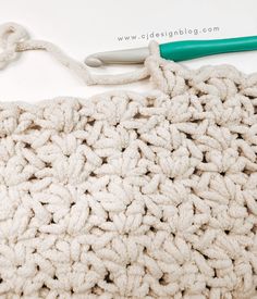 the crochet bag is next to a green handled knitting needle