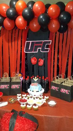 a table topped with cakes and cupcakes covered in red, black and white frosting