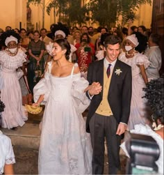 a bride and groom walking down the aisle in front of a large group of people