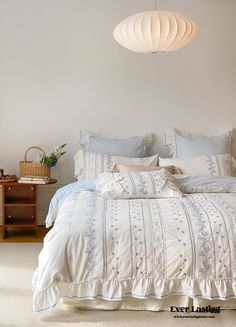 a bed with white sheets and pillows in a bedroom next to a lamp hanging from the ceiling