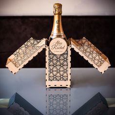 a bottle of champagne sitting on top of a table next to a box with cut outs