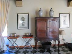 a living room with checkered flooring and pictures on the wall, including an armoire