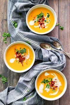 three bowls of creamy carrot soup with bacon