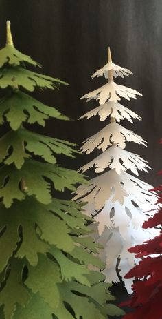 three paper christmas trees are shown in the foreground, one is red and green