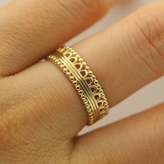 a woman's hand wearing a gold ring with filigrees on it