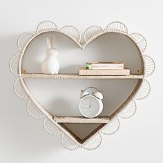 a heart shaped shelf with two shelves holding books and an alarm clock