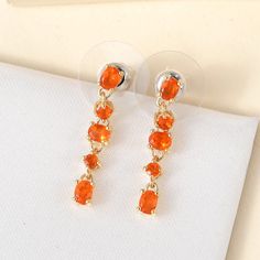 Inspired by the autumn season, these crimson fire opal earrings have a beautiful appearance symbolizing abundance. The beautifully hued modern October birthstone arranges in different shapes to represent the falling of ripened leaves, a picturesque common during autumn. The east-west arrangement of the middle gemstone gives a contemporary look highlighting its beauty and sparkle. These dangle earrings are crafted in sterling silver and can be styled with any outfit. The easy post-stud on the back allows hassle-free wearing.  Item Details- Metal- Sterling Silver Stone- Mexican Fire Opal Shape- Oval 5x3mm and Round 2.5mm Setting- Prong Finish- Yellow Gold Plating Orange Gemstone Drop Earrings, Orange Gemstone Dangle Earrings, Orange Dangle Earrings For Formal Occasions, Fire Opal Earrings, Autumn Season, October Birthstone, Dangling Earrings, Opal Earrings, East West