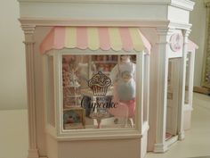 a toy store with pink and yellow awnings on the front window, an open cupcake display case behind it