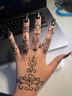 a woman's hand with tattoos on it next to a laptop