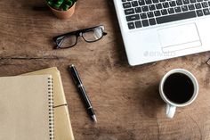 an open laptop computer sitting on top of a wooden table next to a cup of coffee