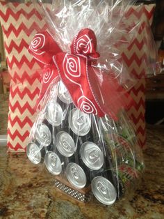 a red and white gift bag filled with soda cans sitting on top of a counter