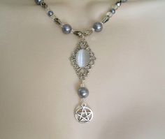 "This beautiful necklace has a grey catseye set on a sterling silver plated pendant, pewter silver pentacle, grey pearl beads, clear czech glass beads, seed beads and pewter silver accent beads. 18\" long. Sterling silver plated toggle clasp." Witch Necklace Aesthetic, Witch Pentagram, Gothic Jewelry Diy, Pentacle Necklace, Wicca Jewelry, Witchcraft Magic, Pagan Necklace, Wiccan Necklace, Pentagram Necklace