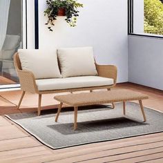 a white couch sitting on top of a wooden floor next to a table and potted plant